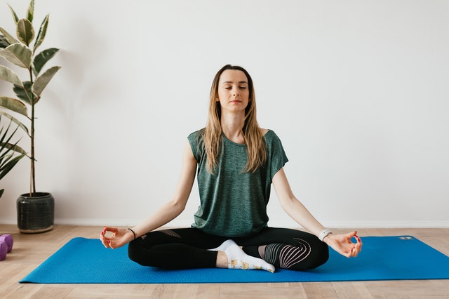 woman sitting in crossed legged position doing mindful body scan of herself