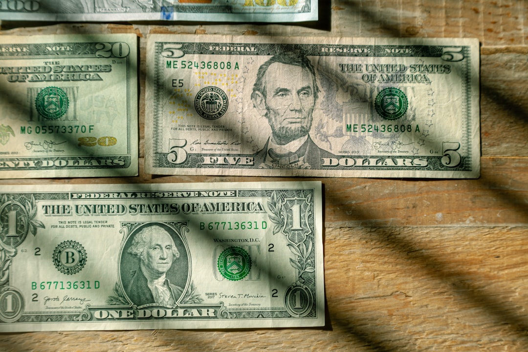 US Currency $100, $20, $5, $1 denominations flat lay on wood background