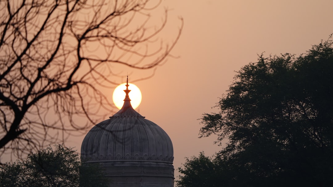 The sun is setting behind a building with a dome