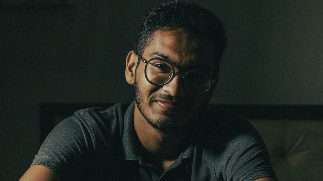 man in black framed eyeglasses and black collared shirt
